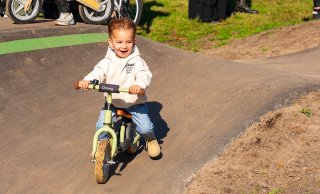 een peuter die over een heuvel fietst met een loopfiets